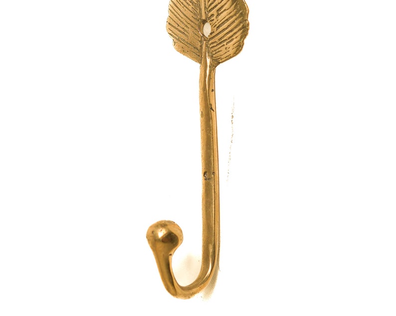 May include: A gold leaf-shaped hook with a decorative design. The hook is made of metal and has a simple, elegant design.