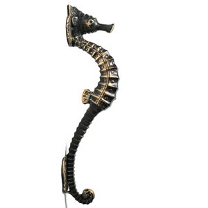 May include: A black and gold metal seahorse door handle. The handle is shaped like a seahorse with a curled tail and a detailed design.
