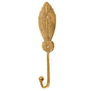 May include: A gold leaf-shaped hook with a decorative design. The hook is made of metal and has a smooth finish.