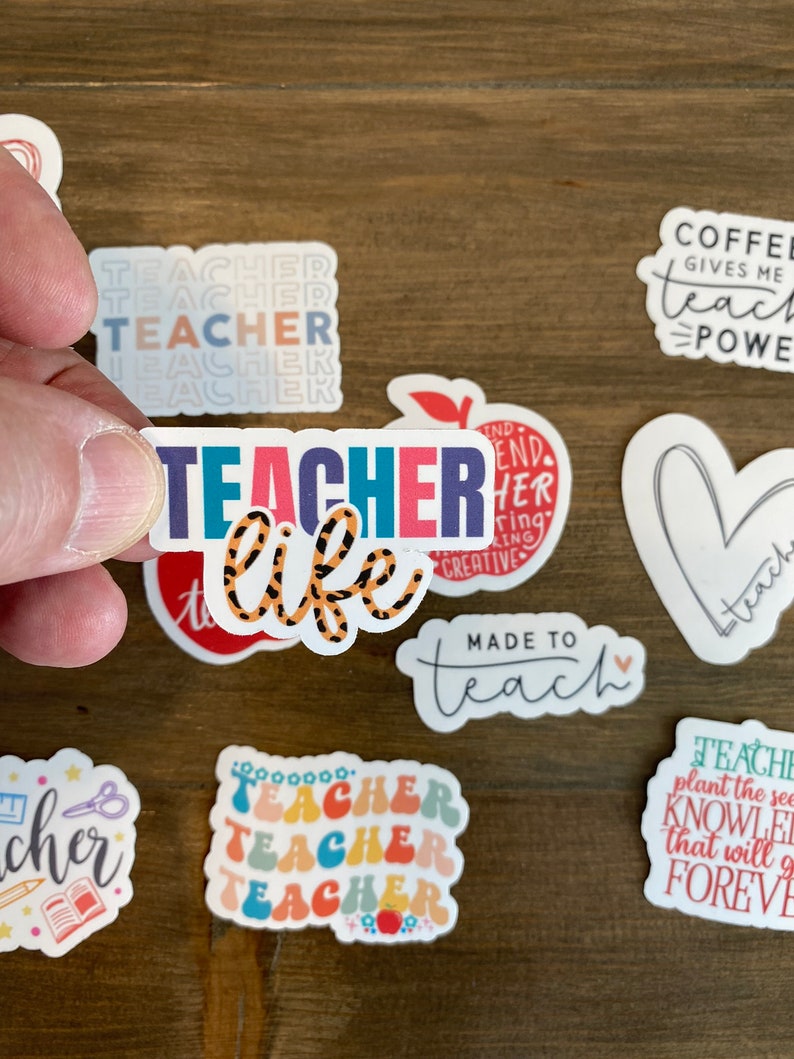May include: A collection of colorful teacher stickers with various designs and phrases, including "Teacher Life", "Made to Teach", and "Coffee Gives Me Teach Power".