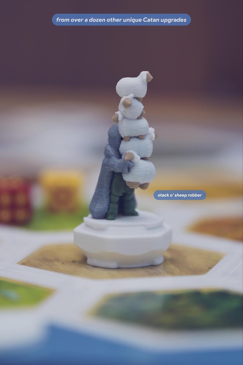 May include: A 3D printed game piece featuring a figure in a grey cloak and green clothing holding a vertical stack of five white sheep. The piece stands on a white circular base. Text on the image reads: from over a dozen other unique Catan upgrades and stack o' sheep robber.