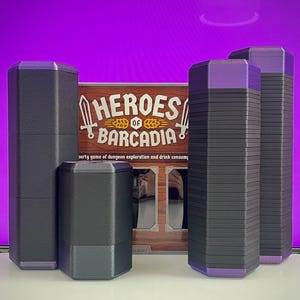 Puede incluir: Un juego de mesa llamado "Heroes of Barcadia" con piezas de juego negras y moradas. Las piezas son hexagonales y cilíndricas. La caja del juego es visible en el fondo, con el título y una descripción.