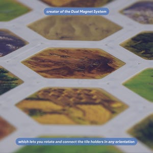 May include: A board game component featuring a white grid of hexagonal tile holders with various landscape illustrations. The text "creator of the Dual Magnet System" and "which lets you rotate and connect the tile holders in any orientation" is visible.