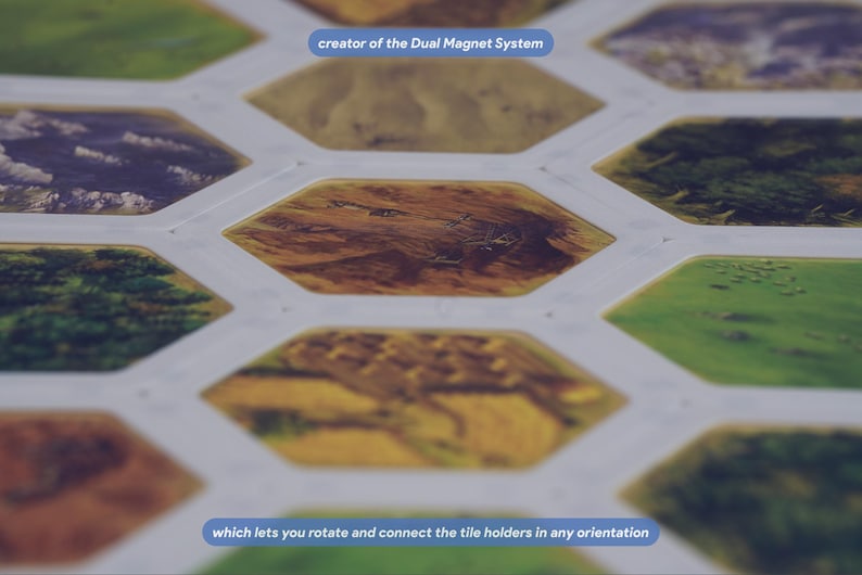 May include: A board game component featuring a white grid of hexagonal tile holders with various landscape illustrations. The text "creator of the Dual Magnet System" and "which lets you rotate and connect the tile holders in any orientation" is visible.