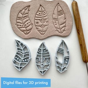 Könnte beinhalten: Drei federförmige Ton-Ausstecher und drei Federeindrücke in Ton. Die Ausstecher sind weiß und haben detaillierte Designs. Der Ton ist hellbraun. Rechts befindet sich ein Holzwerkzeug. Der Text unten lautet "Digitale Dateien für 3D-Druck".