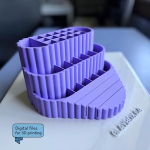 Op de afbeelding: Een drielaagse, lavendelkleurige organizer met meerdere compartimenten. De organizer heeft een gegroefd ontwerp aan de zijkanten en is gelabeld met "Digital files for 3D printing". De basis is licht van kleur met de tekst "CLAYBOX CA".