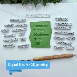 Puede incluir: Un conjunto de sellos de plástico blanco con nombres de hierbas, una forma de arcilla verde con nombres de hierbas en relieve y una herramienta de madera. El texto "Rosemary, Thyme, Marjoram, Sage, Dill" es visible. El texto "Digital files for 3D printing" también es visible.