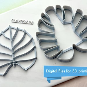May include: Two 3D printed cookie cutters in the shape of monstera leaves. The cutters are made of a light gray plastic and are designed for use with fondant or cookie dough.
