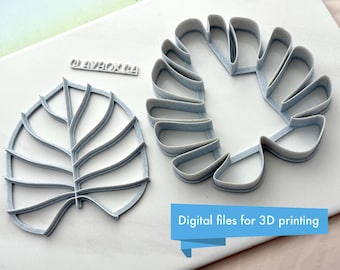 May include: Two 3D printed cookie cutters in the shape of monstera leaves. The cutters are made of a light gray plastic and are designed for use with fondant or cookie dough.