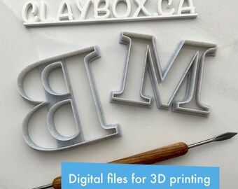 May include: White plastic letters spelling "CLAYBOX.CA" and two white plastic letters "B" and "M" on a white surface. The letters are for 3D printing. The text "Digital files for 3D printing" is on a blue and white banner.