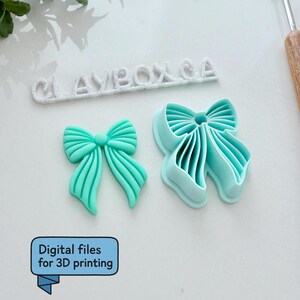 Op de afbeelding: Twee turquoise strikvormige items. E&eacute;n is een effen strik en de andere is een strikvormige uitsteker. De tekst "CLAYBOX CA" staat boven de strikken. De tekst "Digitale bestanden voor 3D-printen" staat in een blauw kader.