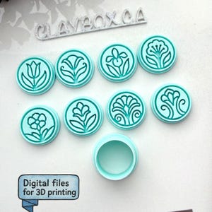 May include: A set of eight circular light blue stamps featuring various embossed floral designs, along with one empty circular stamp base. The text CLAYBOX.CA is visible at the top, and a label reads Digital files for 3D printing.