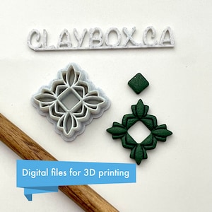 May include: Three 3D printed cookie cutters in the shape of a square with a floral design. The cutters are white, green, and dark green. The text "CLAYBOXCA" is printed on a white surface behind the cutters. The text "Digital files for 3D printing" is printed on a wooden surface in the bottom left corner of the image.