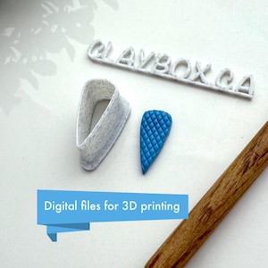 May include: White 3D printed mold for making a teardrop-shaped polymer clay pendant. The mold is next to a blue polymer clay pendant with a quilted texture. The text "CLAYBOX.CA" is visible in the background.