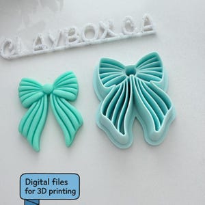 Op de afbeelding: Een turquoise strikvormige koekjessnijder en een turquoise strikvormige fondant. De koekjessnijder staat naast de fondantstrik. De tekst "CLAYBOX CA" staat boven de strik en de snijder. De tekst "Digital files for 3D printing" staat in een blauw kader.