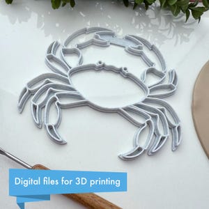 May include: A light gray crab-shaped 3D printing template. The template is made of a light gray material and has a detailed outline of a crab. The text "Digital files for 3D printing" is in a blue banner at the bottom.