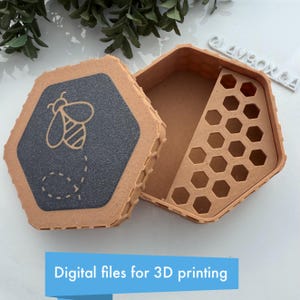 May include: Hexagonal box with a bee design on the lid, open to reveal a honeycomb interior. The lid is dark grey with a light brown bee illustration and dotted trail. The box is light brown. Text at the bottom reads "Digital files for 3D printing."