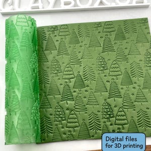 May include: A green rolling pin and a green sheet with an embossed Christmas tree pattern. The rolling pin is cylindrical with a repeating tree design. The sheet has a repeating pattern of various Christmas trees. Text on the bottom right says "Digital files for 3D printing."