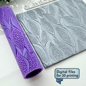 Puede incluir: Un rodillo cilíndrico morado y una lámina rectangular gris, ambos con un patrón en relieve de mazorcas de maíz texturizadas con hojas. Un pequeño cartel azul muestra el texto Digital files for 3D printing en letras negras.