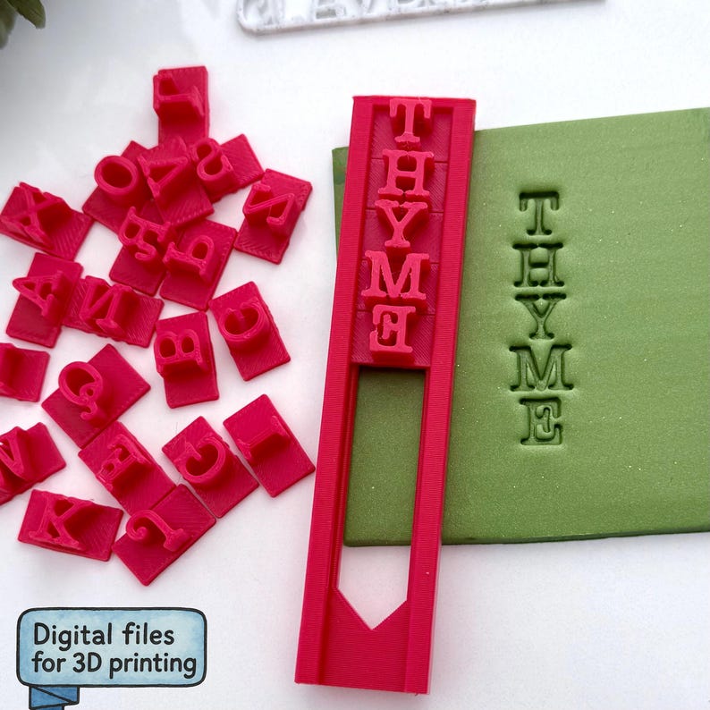 May include: A collection of red 3D-printed letter stamps and a stamp holder spelling "THYME". The word "THYME" is also stamped on a green surface. The image includes the text "Digital files for 3D printing".