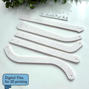 May include: Five white, curved, textured pieces with small holes, likely for a craft project, are arranged on a white surface. The text "CLAYBOX 04" is visible in the background. The image also includes the text "Digital files for 3D printing".