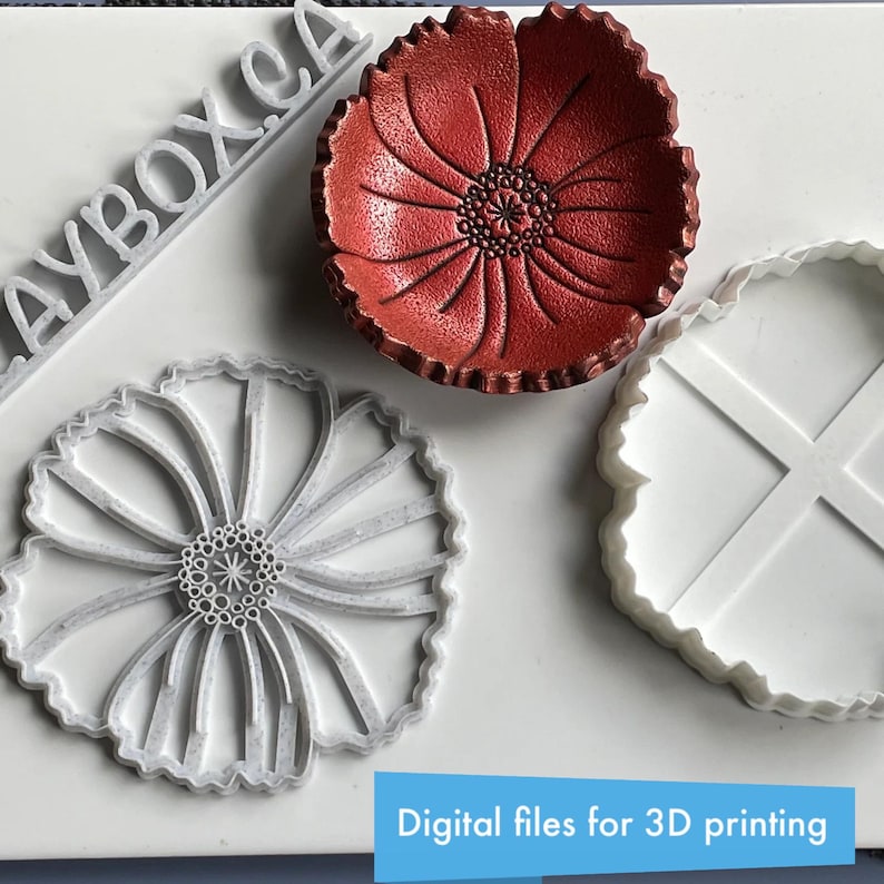May include: A red poppy-shaped bowl and two white flower-shaped objects. The bowl has a textured surface and a detailed center. The white objects appear to be molds or cutters. Text at the bottom reads "Digital files for 3D printing."