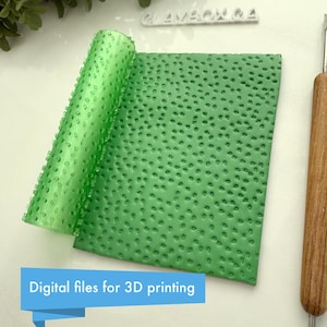 Puede incluir: Rodillo de impresión 3D verde con una superficie texturizada. El rodillo está diseñado para crear un patrón de pequeños puntos en fondant o arcilla.