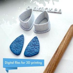 May include: Two blue polymer clay earrings with a floral pattern, a pair of white 3D printed molds for making the earrings, and a wooden rolling pin. Digital files for 3D printing.