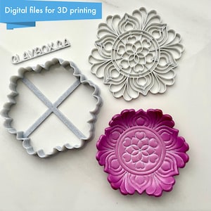 May include: Three 3D printed molds for making decorative items. The molds are in the shape of a square, a circle, and a flower. The square mold has a cross design inside. The circle mold has a floral design inside. The flower mold is a solid piece with a floral design. The molds are all gray.