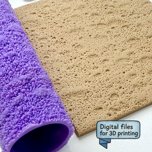 Puede incluir: Un rodillo de textura cilíndrico de color morado con un patrón de superficie denso y poroso junto a una hoja cuadrada plana de color tostado con una textura de cráteres idéntica. Se ve un pequeño letrero azul con el texto Digital files for 3D printing.