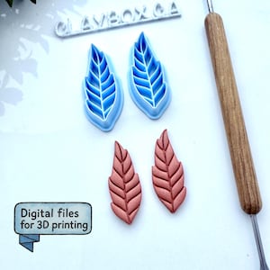 Op de afbeelding: Een verzameling bladvormige gereedschappen voor het knutselen. Twee blauwe bladvormige uitsteekvormen en twee koperkleurige bladafdrukken worden getoond. Een gereedschap met houten handvat is rechts geplaatst. De tekst in de afbeelding luidt "Digitale bestanden voor 3D-printen".