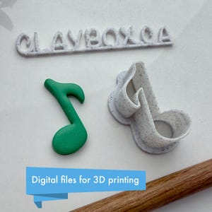 May include: A white 3D printed cookie cutter in the shape of a musical note. The cutter is on a white surface with a green 3D printed musical note next to it. The text "CLAYBOXCA" is printed in white on a white surface above the cutters. The text "Digital files for 3D printing" is printed in blue on a light blue background.