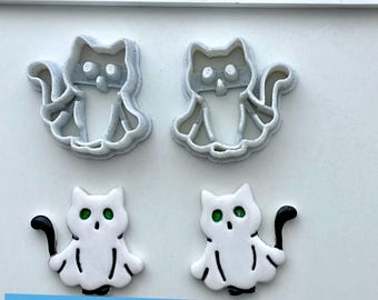 Peut inclure: Quatre objets en forme de chat. Deux sont des emporte-pièces en plastique gris et deux sont blancs avec des yeux verts et des queues noires. Le texte "Digital files for 3D printing" est dans un rectangle bleu en bas de l'image.