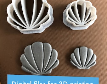 Puede incluir: Cuatro cortadores de galletas de concha marina impresos en 3D en dos tamaños. Los cortadores más grandes son blancos con un acabado moteado, mientras que los cortadores más pequeños son de color plateado metálico.