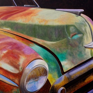 May include: Close-up of a vintage car's hood, painted in a vibrant mix of green, orange, and red hues. The paint is chipped and faded, revealing the metal underneath. The car's chrome headlight and emblem are visible.