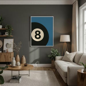 Puede incluir: Un cuadro enmarcado con un dise&ntilde;o estilizado de la bola ocho de billar. La obra presenta una bola ocho en blanco y negro sobre un fondo azul. La impresi&oacute;n est&aacute; en un marco blanco y se muestra en una pared gris oscuro. Dise&ntilde;o moderno y minimalista.