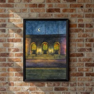 Puede incluir: Una pintura de acuarela enmarcada representa una escena nocturna de un edificio con ventanas arqueadas. Las ventanas están iluminadas y una luna creciente y estrellas son visibles en el cielo azul oscuro. La pintura está en un marco negro.