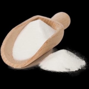 以下が含まれることがあります： 白い粉末で満たされた木製のさじ。黒い表面に粉末が少しこぼれている