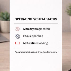 Può includere: Una carta bianca con il testo "OPERATING SYSTEM STATUS". La carta mostra lo stato della memoria, della concentrazione e della motivazione, con la raccomandazione di riprovare domani. La carta è su una superficie di legno.