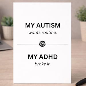 Può includere: Una carta bianca con testo nero che recita "MY AUTISM wants routine." e "MY ADHD broke it." Un ingranaggio grafico è tra le due frasi. La carta è su una superficie di legno con una penna e piccole piante in vaso sullo sfondo.
