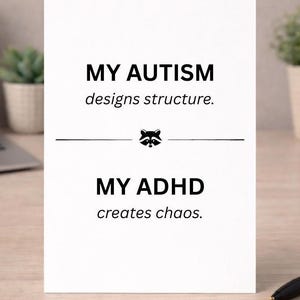 Può includere: Una carta bianca con testo nero che recita "MY AUTISM designs structure." e "MY ADHD creates chaos." Una grafica di procione è tra le due affermazioni. La carta è su una scrivania con una penna e una piccola pianta.