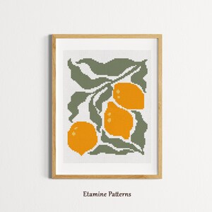 May include: A framed cross-stitch artwork featuring a botanical design of three bright orange lemons and green leaves. The artwork is set against a white background and framed in a light wood frame. The text "Etamine Patterns" is at the bottom.