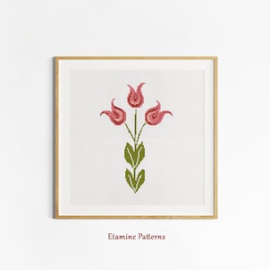 May include: A cross-stitch pattern featuring a stylized floral design with three pink tulips and green leaves. The pattern is framed in a light wood frame.