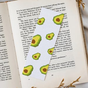 May include: A white bookmark with a repeating pattern of green avocado halves. The bookmark is 6 inches long.
