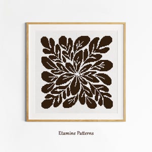 May include: A framed cross-stitch pattern featuring a symmetrical design of dark brown leaves arranged in a circular pattern. The artwork is set against a white background and framed in a light brown wooden frame. The text "Etamine Patterns" is at the bottom.