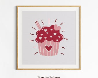 May include: A framed cross-stitch pattern of a cupcake with a heart on the bottom and hearts on top. The cupcake is red and pink with a straw and radiating lines. The text "Etamine Patterns" is at the bottom.