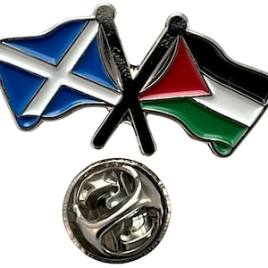 May include: A silver pin featuring a crossed Scottish and Palestinian flag design. The Scottish flag is blue with a white diagonal cross. The Palestinian flag is black, white, green, and red. The pin has a silver back with a safety clasp.