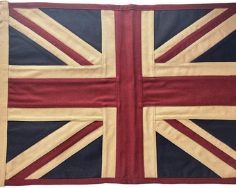 May include: A rectangular flag featuring the Union Jack design. The flag has a navy blue background with red and beige stripes forming the cross and diagonal lines. A beige canvas border with grommets is on the left side.