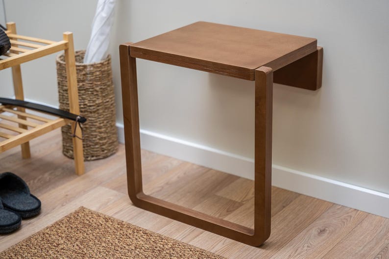 Dark birch plywood folding wall chair unfolded for seating, minimalist and space-saving design.