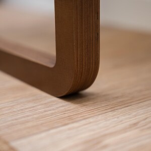 Edge view of dark birch plywood folding wall chair showing smooth rounded join and sturdy design.
